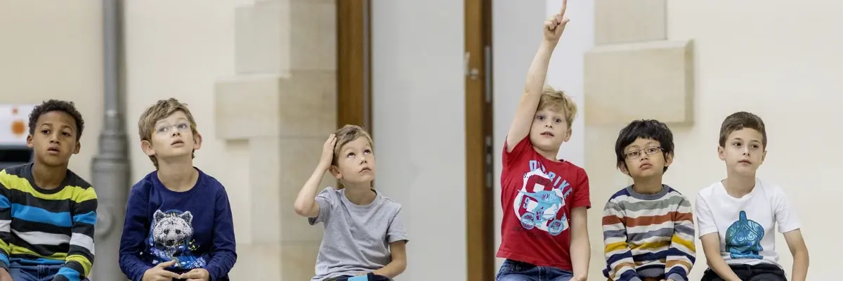 Kinder sitzen auf einer Bank im Museum