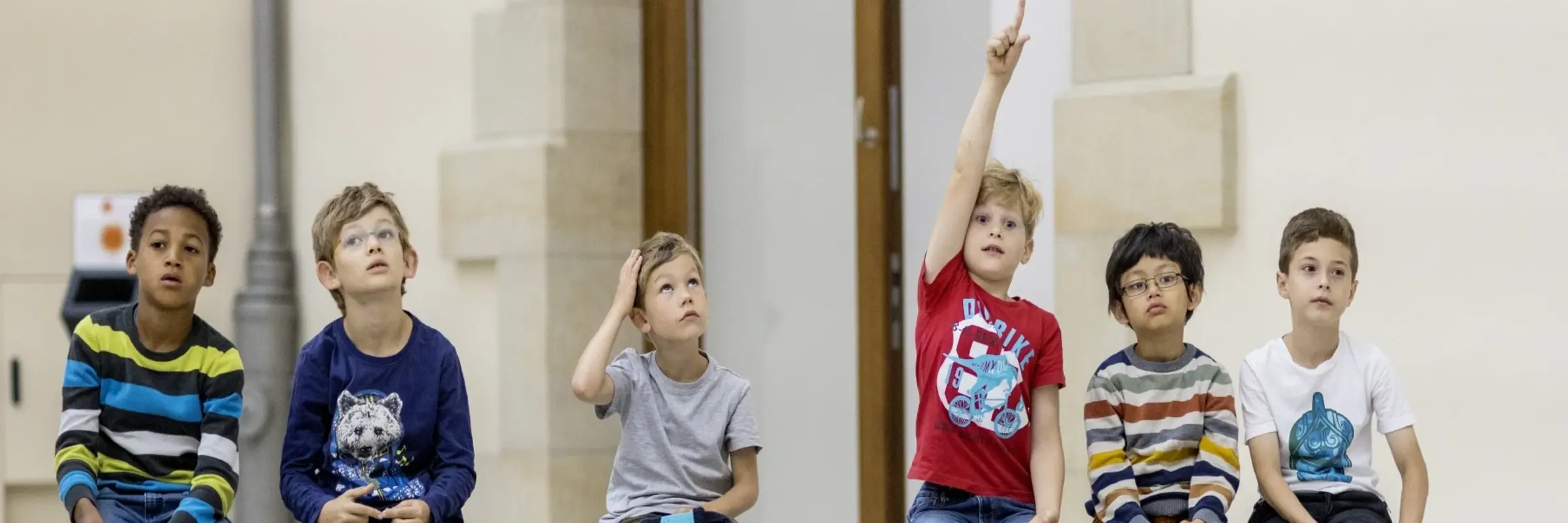 Kinder sitzen auf einer Bank im Museum