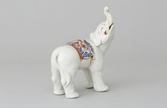 Foto, weißer Elefant aus Porzellan mit in die Höhe gerecktem Rüssel und farbiger Decke über dem Rücken