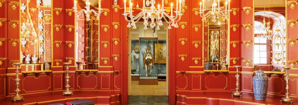 Raumansicht mit roten Wänden und goldenen Kronleuchtern